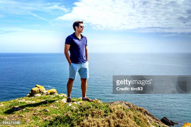 single brazilian man lifestyle portrait at beach headland - dyfed stock pictures, royalty-free photos & images