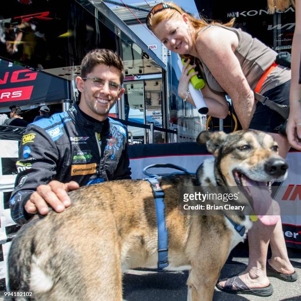 Jordan Taylor pats a dog during the fan autograph session before the IMSA WeatherTech race at Canadian Tire Motorsport Park on July 6, 2018 in...