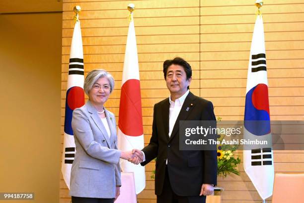 South Korean Foreign Minister Kang Kyung-wha and Japanese Prime Minister Shinzo Abe shake hands prior to their meeting on the sidelines of the...