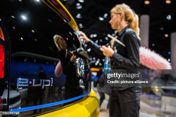 Woman cleans the rear-view window of a Volkswagen 'e-Up!' at the stand of VW at the International Automobile Fair in Frankfurt/Main, Germany, 12...