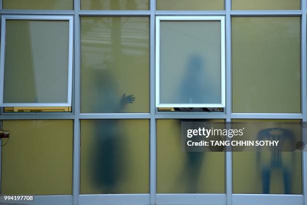 People are pictured through the windows at the hospital where the boys rescued after being trapped in a nearby cave for nearly two weeks have being...