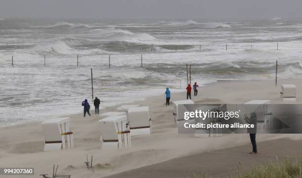 Several people stand at the beach during stormy weather on Wangerooge, Germany, 13 September 2017. Photo: Peter Kuchenbuch-Hanken/dpa