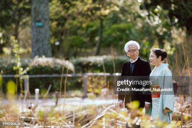 asian couple of gray hair senior and kimono woman who are walking in park - masafumi nakanishi imagens e fotografias de stock