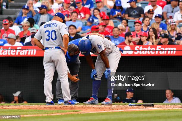 Los Angeles Dodgers right fielder Yasiel Puig is looked at by the trainer and manager Dave Roberts during a MLB game between the Los Angeles Dodgers...