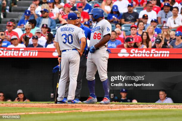 Los Angeles Dodgers right fielder Yasiel Puig is looked at by the trainer and manager Dave Roberts during a MLB game between the Los Angeles Dodgers...