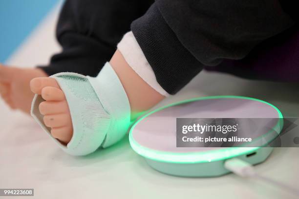 Measuring device called Owlet Smart Sock which checks blood pressure, heart rhythm, and blood oxygen levels is attached to the foot of a baby doll at...