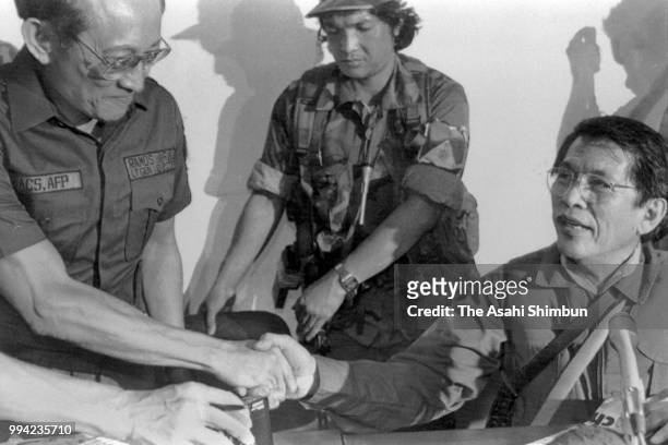National Defense Minister Juan Ponce Enrile shakes hands with Chief of the Philippine Constabulary Fidel Ramos during a press conference on February...