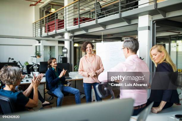 successful businesswoman standing amidst coworkers - applauding leader stock pictures, royalty-free photos & images