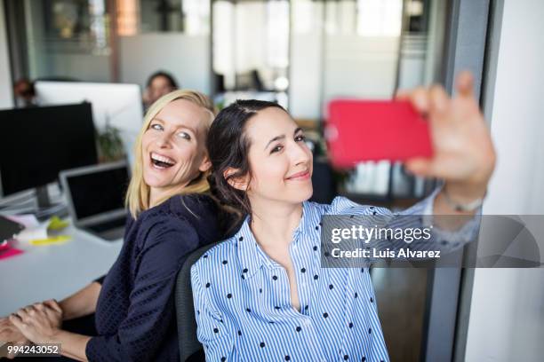 businesswoman taking selfie with female colleague - coworkers stock-fotos und bilder