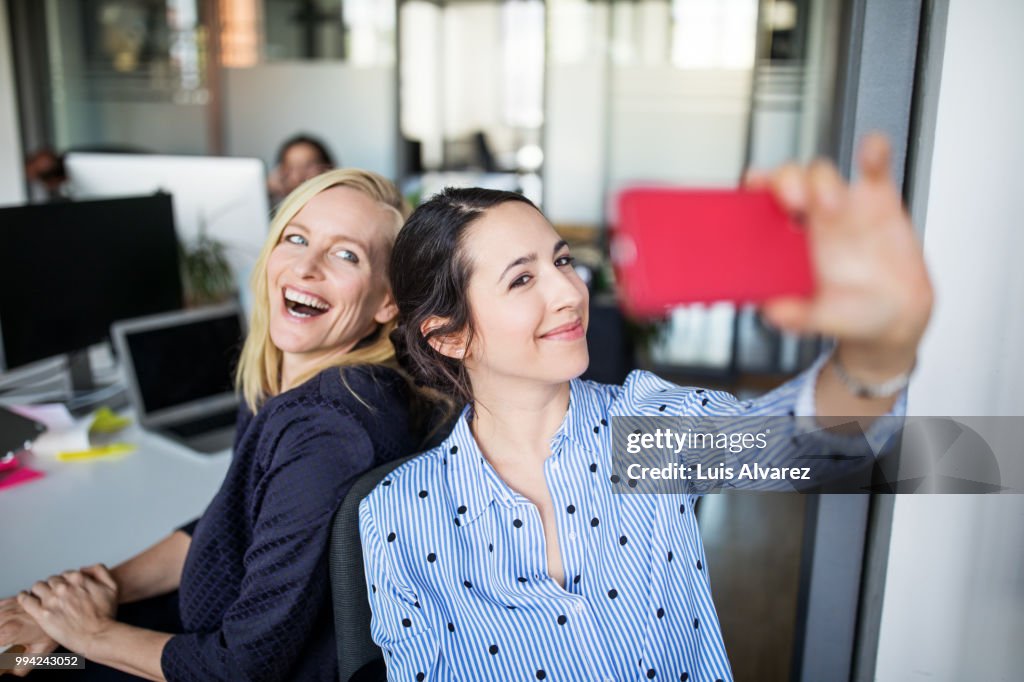 Businesswoman taking selfie with female colleague