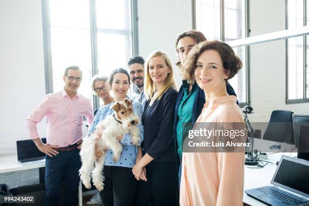 smiling business colleagues standing with dog - technophile stock pictures, royalty-free photos & images