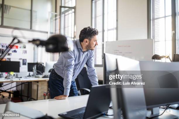 thoughtful businessman leaning on desk at office - technophiler mensch stock-fotos und bilder