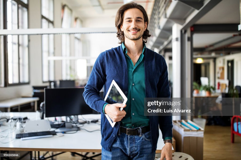 Smiling businessman standing with digital tablet