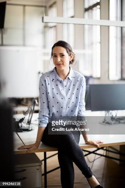 confident businesswoman sitting on desk - legs crossed at knee stock pictures, royalty-free photos & images