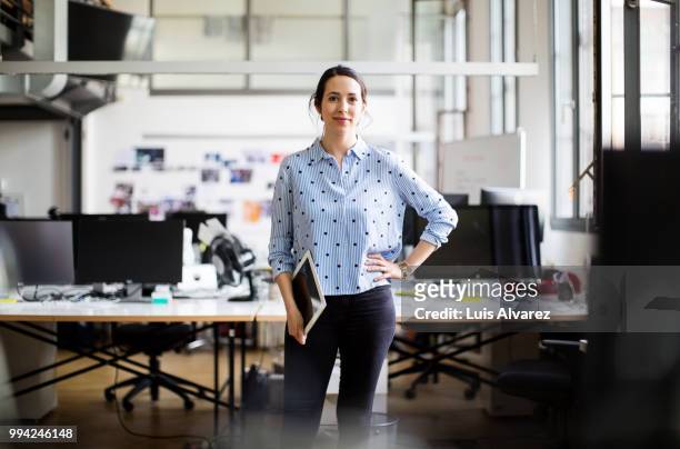 businesswoman standing with digital tablet - nuova impresa foto e immagini stock