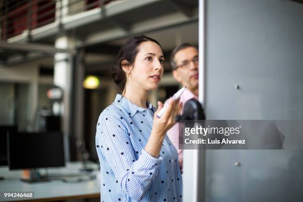 businesswoman looking at whiteboard during meeting - woman whiteboard stock-fotos und bilder