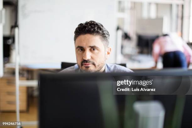 confident software programmer sitting at office - software programmer stock pictures, royalty-free photos & images