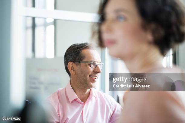 smiling mature businessman with female colleague - meeting pink shirt stock pictures, royalty-free photos & images