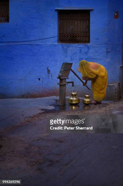 woman filling water pots at a street pump, india - bundi imagens e fotografias de stock