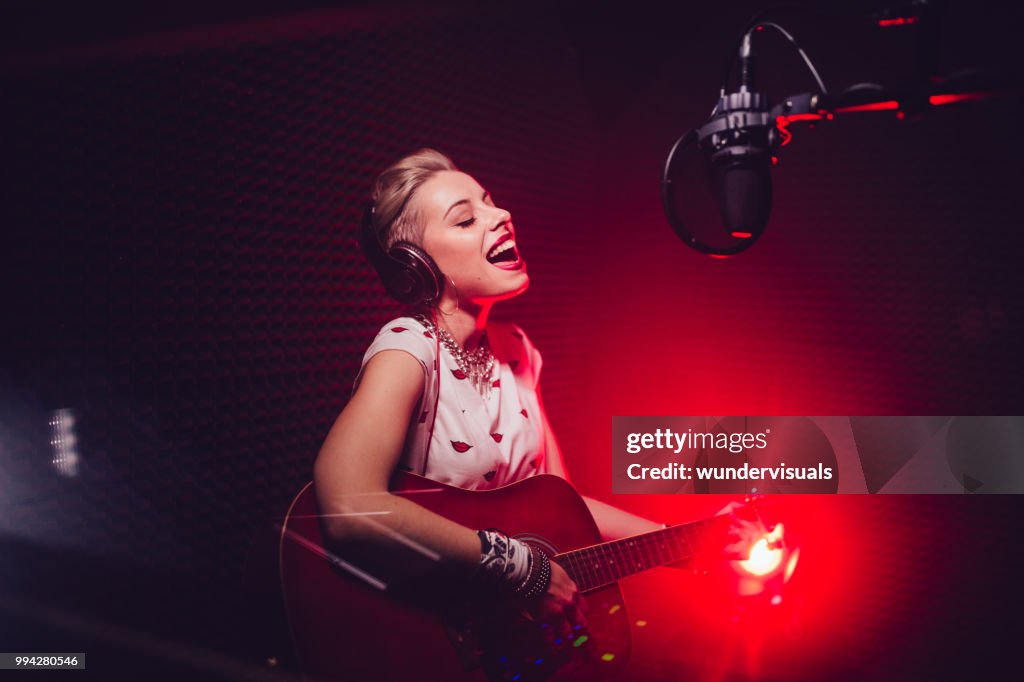 Passionate singer playing the guitar and recording song in studio