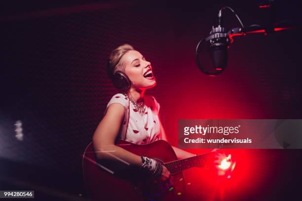 passionate singer playing the guitar and recording song in studio - country and western music stock pictures, royalty-free photos & images