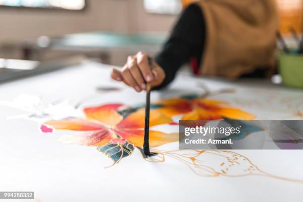woman painting in a batik workshop - malaysian batik fabric stock pictures, royalty-free photos & images