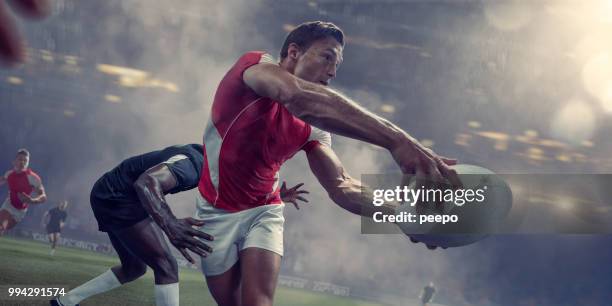 jugador de rugby a pasar la bola justo antes de ser abordado - rugby tournament fotografías e imágenes de stock