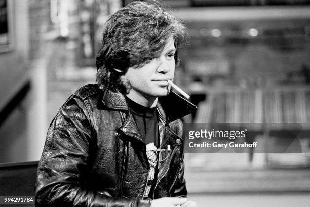 View of American Rock, County, and Folk musician John Cougar, a cigarette in his mouth, during an interview at MTV Studios, New York, New York, May...