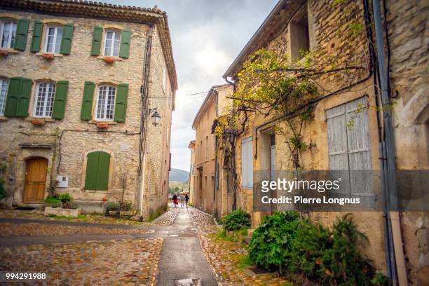 la place de vieux-marché (french for old market square) in the old hight town (haute-ville) of the village of vaison-la-romaine silhouettes walking away in narrow streets - vieux ストックフォトと画像