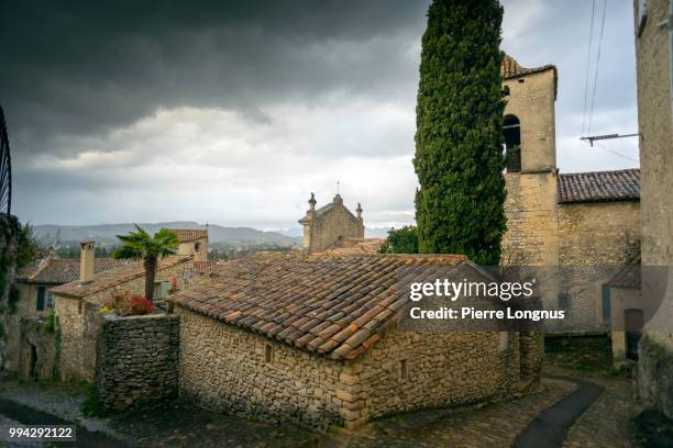 general view of the old higher town of vaison-la-romaine and visible on the right : cathedrale sainte-marie-de-l'assomption under a stormy dark sky - romaine stockfoto's en -beelden