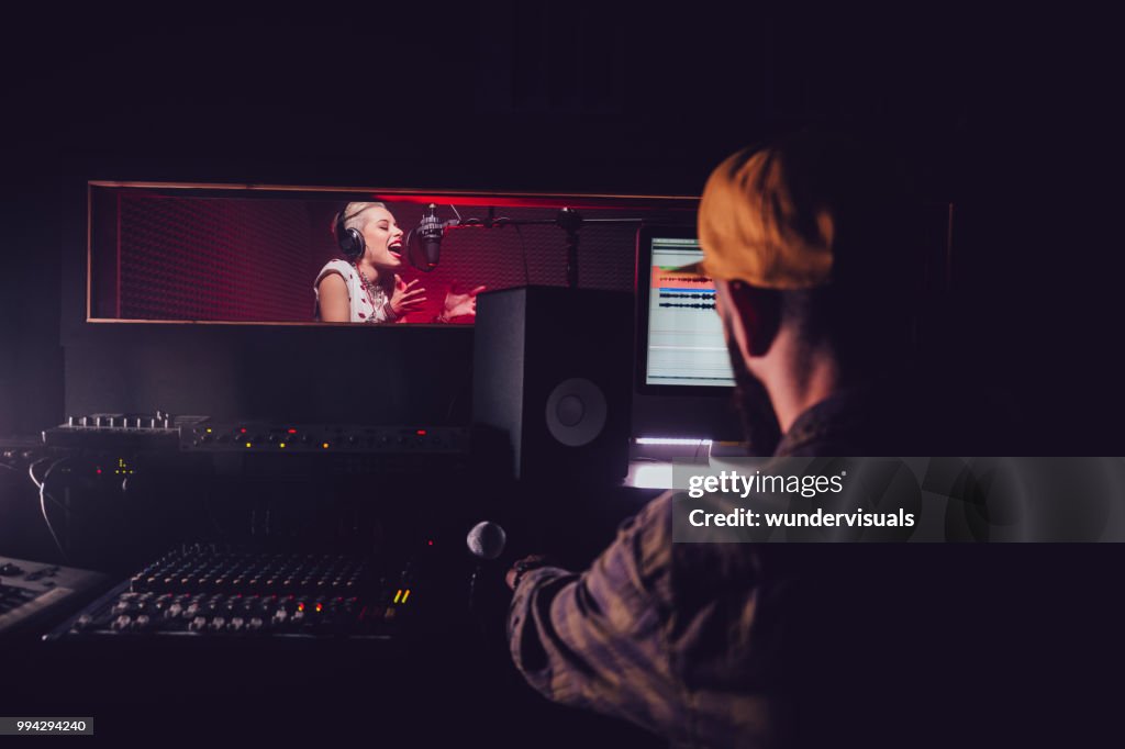 Hipster pop music artist recording song at professional music studio