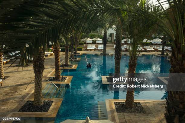 An employee uses a vacuum to clean a swimming pool June 24, 2018 at the Park Hyatt Hotel in Dubai, United Arab Emirates, UAE.