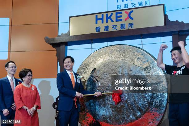 Lei Jun, chairman and chief executive officer of Xiaomi Corp., strikes a gong as Lin Bin, co-founder and president, left, and Laura Cha, chairman of...