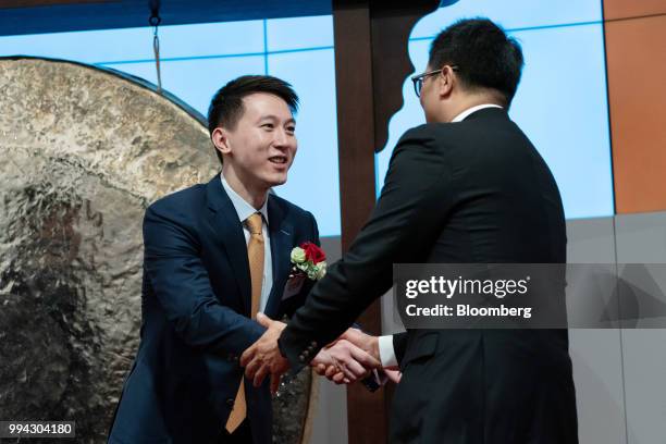 Chew Shou Zi, senior vice president and chief financial officer of Xiaomi Corp., left, shakes hands with a guest during the company's listing...
