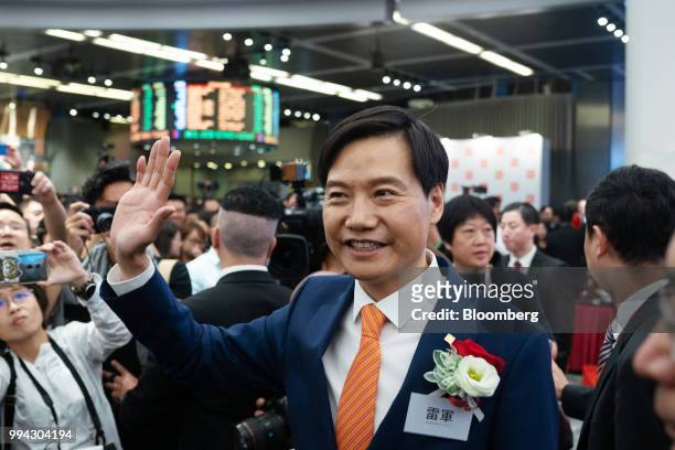 Lei Jun, chairman and chief executive officer of Xiaomi Corp., center, waves during the company's listing ceremony at the Hong Kong Stock Exchange in...
