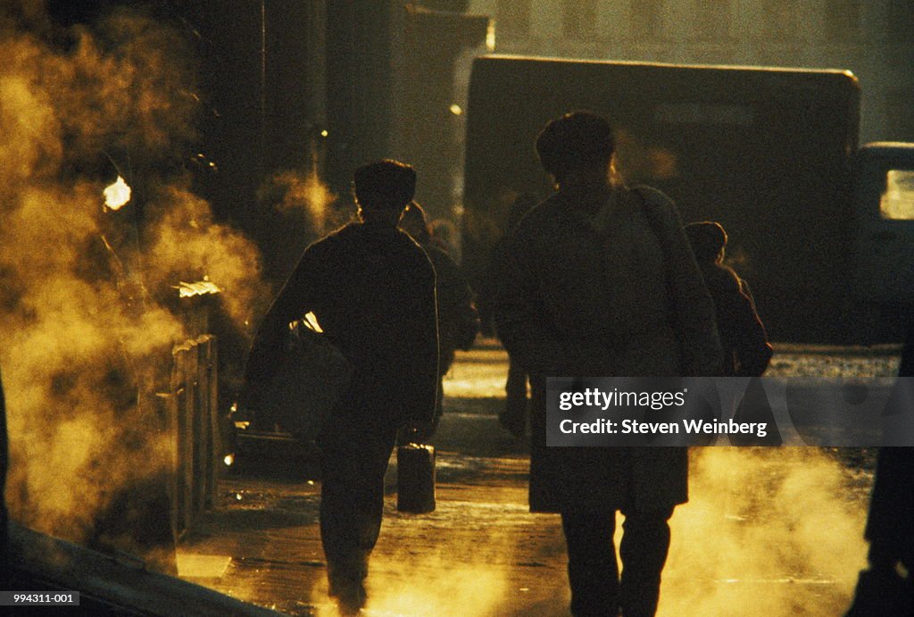 Russia, St Petersburg, commuters walking on street, back-lit