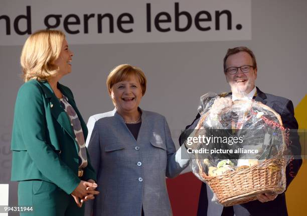 Party member Bernhard Kaster presents German Chancellor Angela Merkel with a gift hamper as Rhineland-Palatinate CDU party chair Julia Kloeckner...
