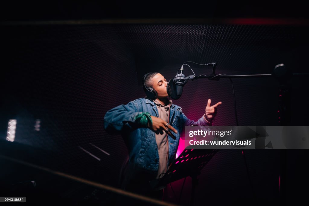 Young hipster African-American rapper recording songs in music recording studio
