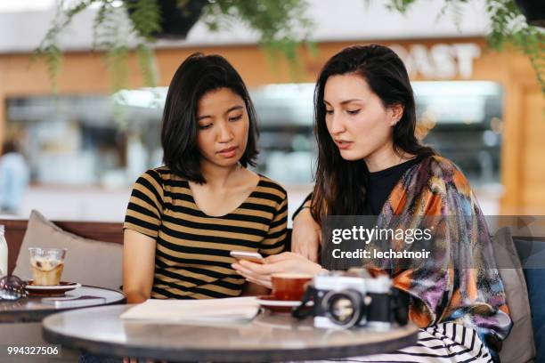 vrienden praten terwijl het hebben van een kopje koffie in bangkok - striped shirt stockfoto's en -beelden