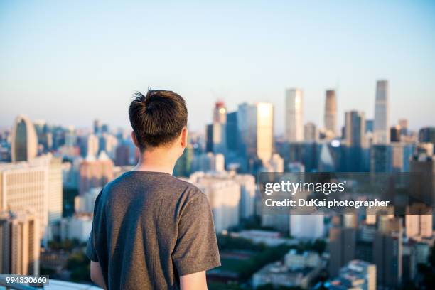 the young man stood on the roof and looked at the cbd - dukai stockfoto's en -beelden