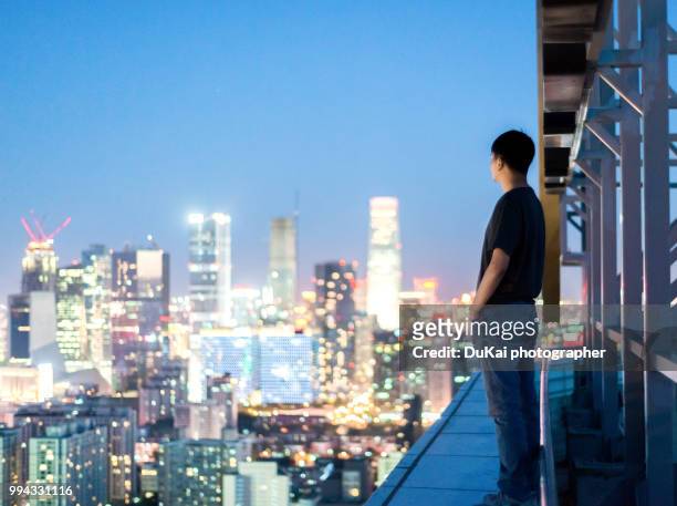 the young man stood on the roof and looked at the cbd - dukai stockfoto's en -beelden