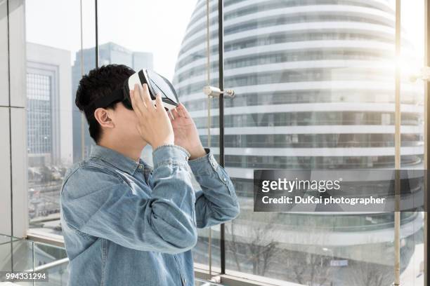 chinese man using the virtual reality headset - dukai stockfoto's en -beelden