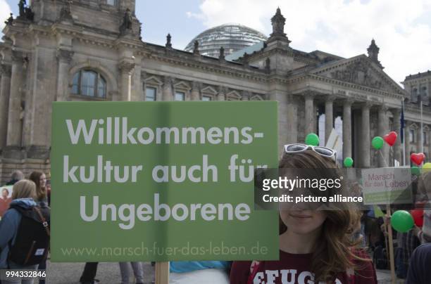 Deborah holds up a sign saying 'Willkommenskultur auch für Ungeboren' during the demonstration 'Marsch fuer das Leben' on the meadow in front of the...