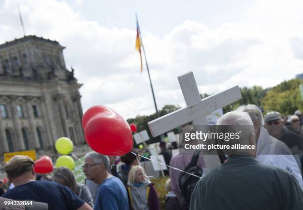 Participant of the demonstration 'Marsch fuer das Leben' holds a white cross on the meadow in front of the Reichstag building in Berlin, Germany, 16...