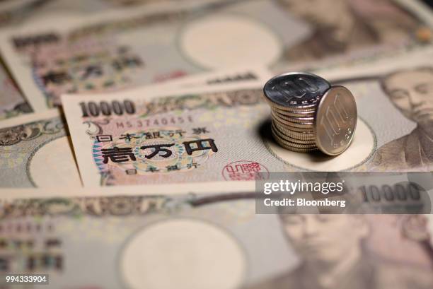 Japanese 100 yen coins and 10,000 yen banknotes are arranged for a photograph in Kawasaki, Kanagawa Prefecture, Japan, on Saturday, July 7, 2018....
