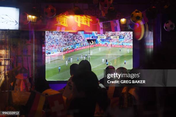 This photo taken on July 6, 2018 shows people watching the 2018 Russia World Cup football match between France and Uruguay, in a bar in Beijing.