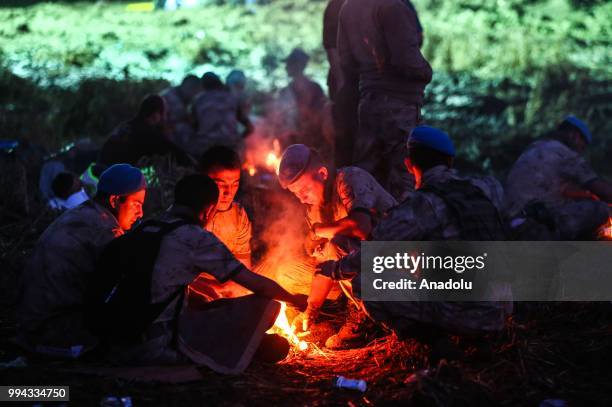Soldiers get warm around a campfire at the scene of the accident after several bogies of a passenger train derailed at the Sarilar village of...