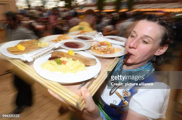 Waitress carries a serving tray with schnitzels and Kaiserschmarrn, a shredded pancake dish, on the opening day of the Oktoberfest funfair in Munich,...
