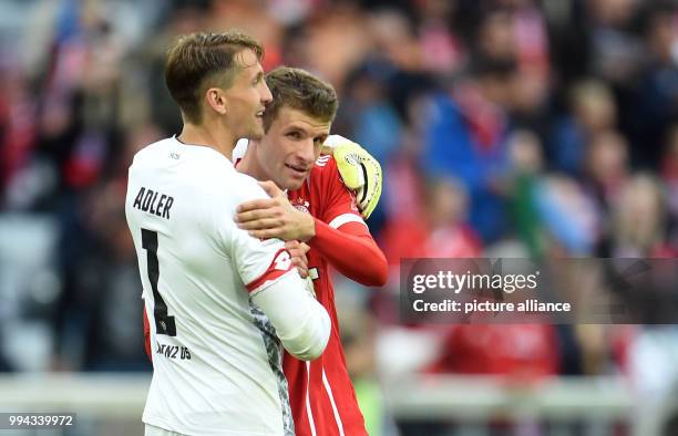 Munich's Thomas Mueller and Mainz' goalkeeper Rene Adler embrace each other after the German Bundesliga soccer match between Bayern Munich and FSV...