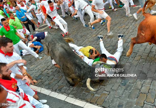 Participants fall next to Cebada Gago fighting bulls on the third day of the San Fermin bull run festival in Pamplona, northern Spain on July 9,...